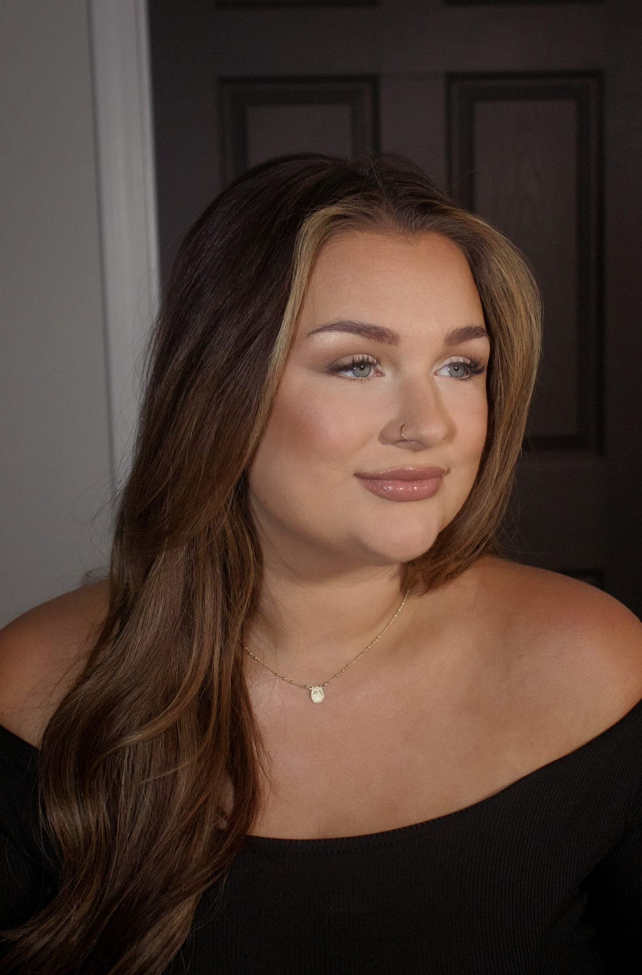 Soft natural bridal glam, eyes cast down, against a quiet studio backdrop